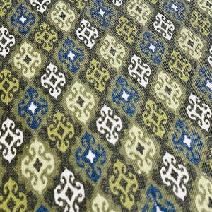 May include: A green, blue, and white fabric with a repeating geometric pattern. The pattern is made up of small squares with a stylized floral design in the center.