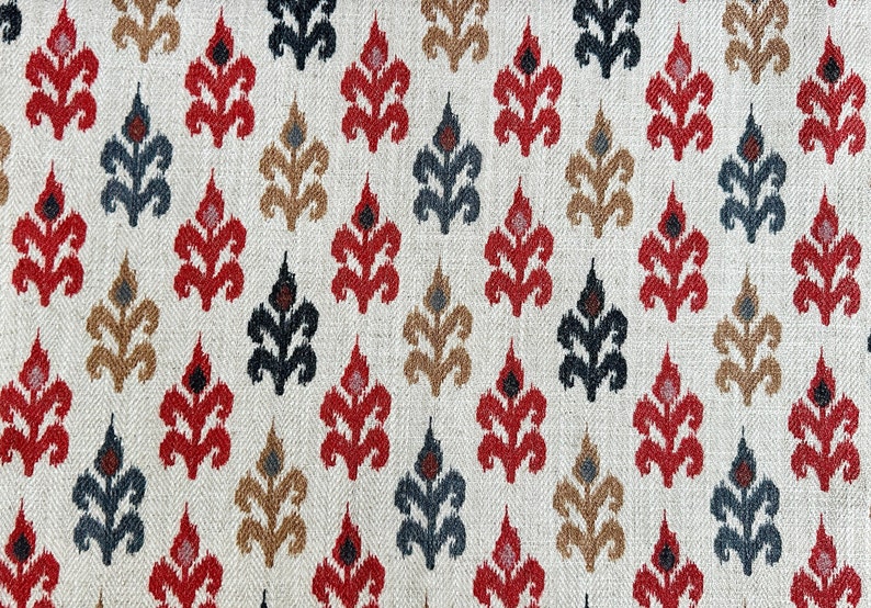 May include: A white fabric with a repeating pattern of red, black, and brown stylized floral motifs. The fabric has a subtle herringbone weave.