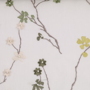 May include: White sheer fabric with embroidered floral designs in shades of green, beige, and yellow. The flowers have pearl accents.