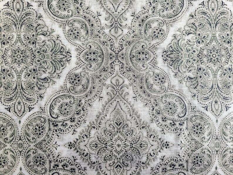 May include: A white fabric with a black and gray paisley pattern. The pattern is intricate and detailed, with a repeating design of paisley shapes and floral motifs.