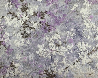May include: A close-up of a fabric with a floral pattern in shades of purple, white, and brown. The fabric has a textured surface and a subtle sheen.