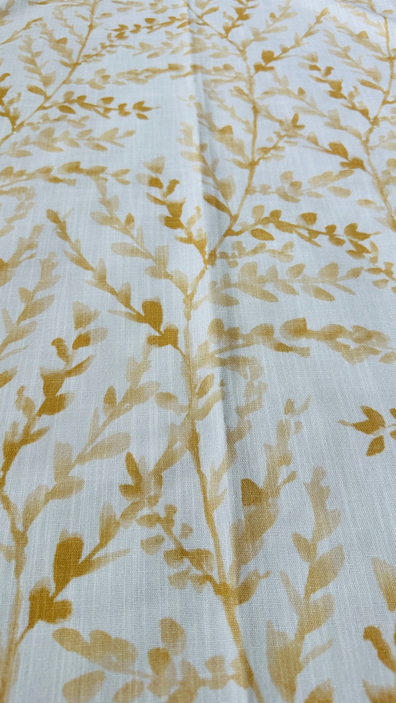 May include: White fabric with a subtle, repeating pattern of gold-colored leaves and branches.