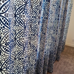 May include: Blue and gray patterned curtains with a geometric design. The curtains are made of a soft, flowing fabric and have a subtle sheen.