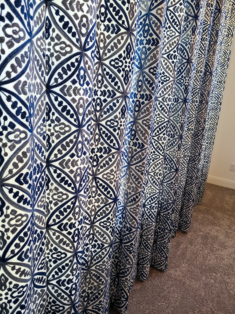 May include: Blue and gray patterned curtains with a geometric design. The curtains are made of a soft, flowing fabric and have a subtle sheen.