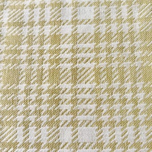 May include: A woven fabric featuring a repeating houndstooth pattern in shades of light olive green and off-white. The textile displays a dense, textured weave with a consistent grid-like structure throughout the entire surface area.