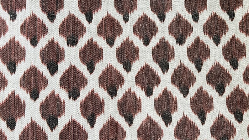 May include: Brown and white fabric with a repeating pattern of brown and black ikat-style shapes.