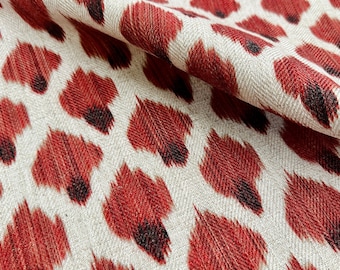 May include: Red and white fabric with a repeating pattern of red, black, and white ikat-style animal print.