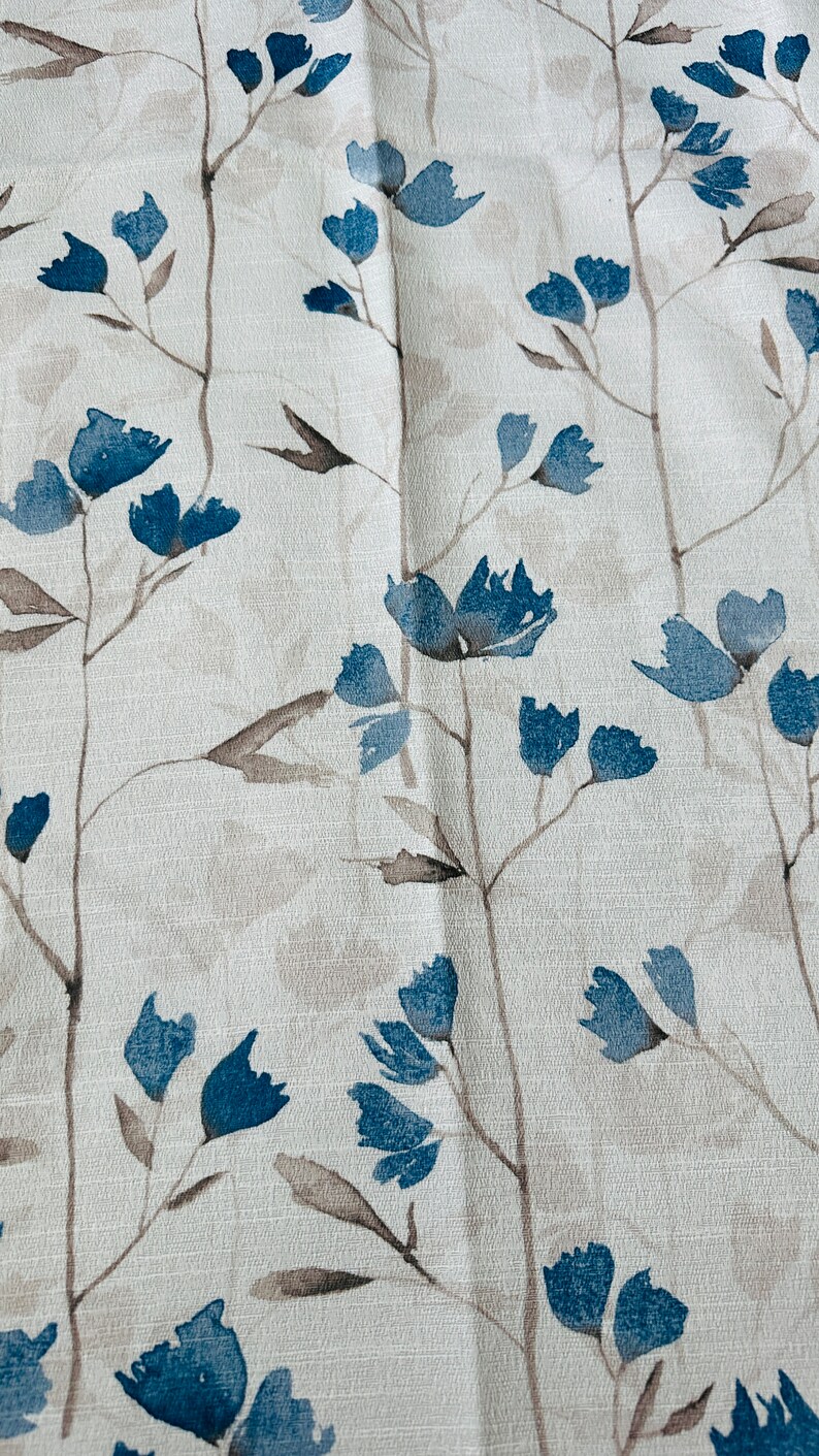 Pu&ograve; includere: Un tessuto bianco con un motivo floreale blu. I fiori sono stilizzati e assomigliano a dipinti ad acquerello.