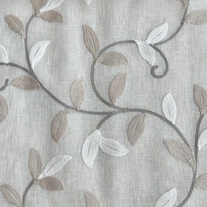 May include: A close-up of a beige fabric with an embroidered design of brown and white leaves and vines.
