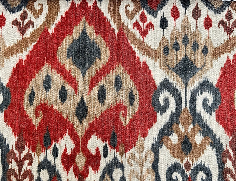 May include: Red, brown and black patterned fabric with an ikat design. The fabric has a woven texture.