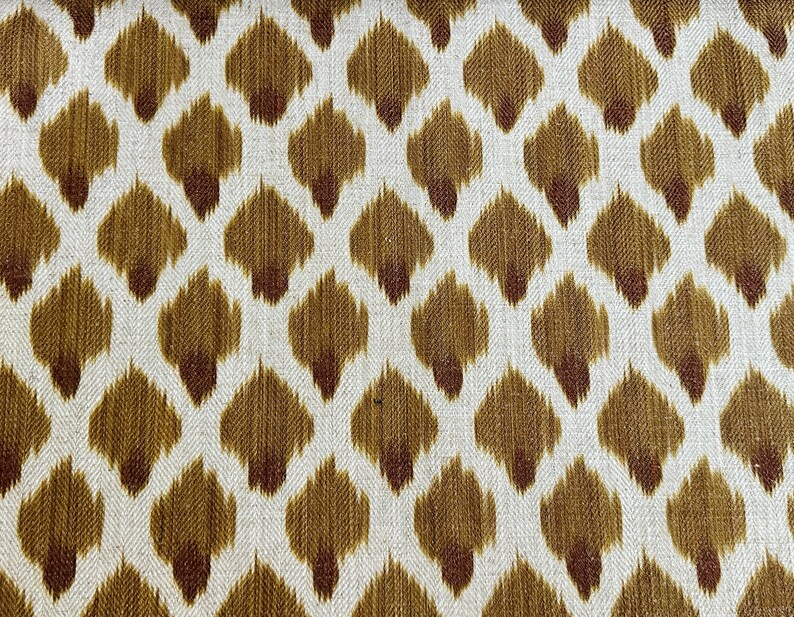 May include: A white fabric with a repeating pattern of brown and maroon teardrop shapes.