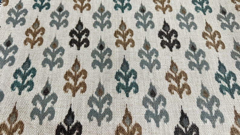 May include: A white fabric with a repeating pattern of stylized leaves in shades of brown, teal, and gray.