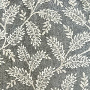 K&ouml;nnte beinhalten: Ein grauer Stoff mit einem wei&szlig;en floralen Muster aus Bl&auml;ttern und Zweigen. Der Stoff hat eine strukturierte Oberfl&auml;che.
