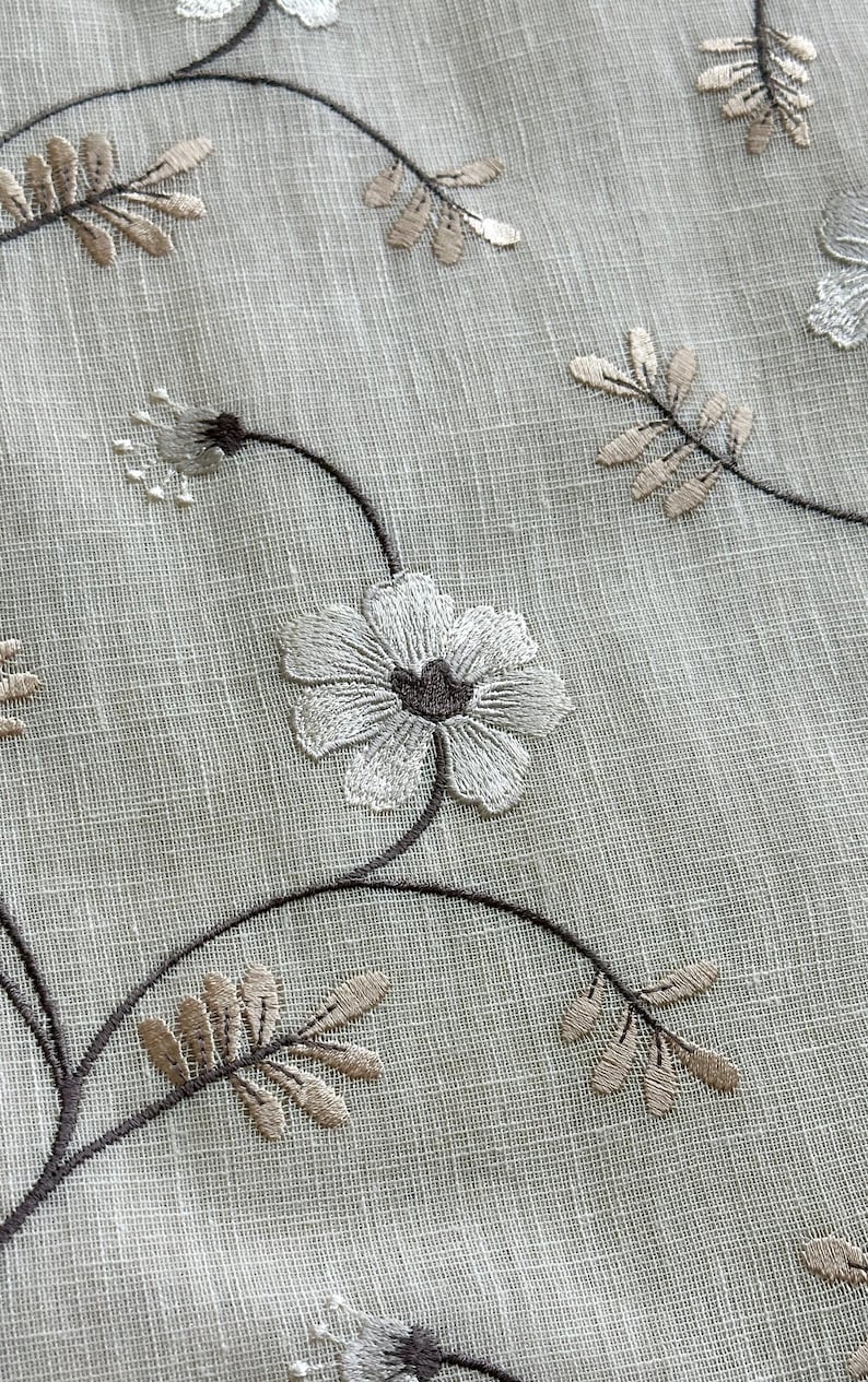 May include: White sheer fabric with embroidered brown vines and white flowers. The fabric has a subtle texture.