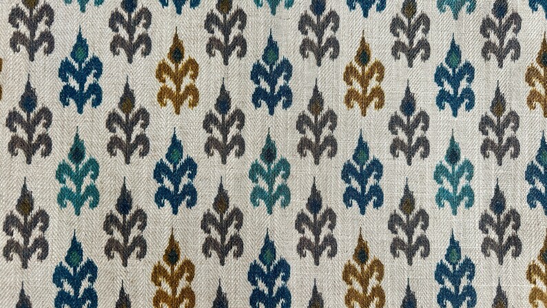May include: A white fabric with a repeating pattern of blue, teal, brown, and gold stylized floral designs.