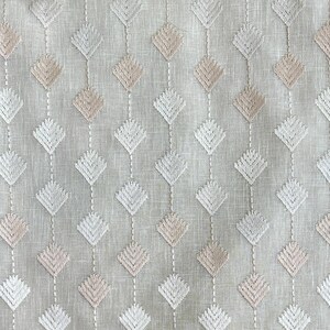 Puede incluir: Una tela blanca con un patr&oacute;n repetido de diamantes bordados en tonos de rosa y blanco.