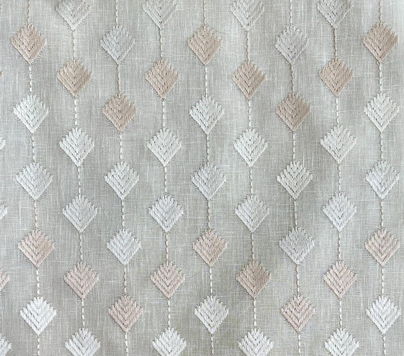 Puede incluir: Una tela blanca con un patr&oacute;n repetido de diamantes bordados en tonos de rosa y blanco.