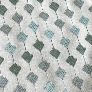 May include: A white fabric with a repeating pattern of light blue and dark green diamond shapes. The fabric has a subtle texture.