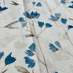 Pu&ograve; includere: Tessuto bianco con un motivo ripetitivo di fiori stilizzati blu e steli marroni.