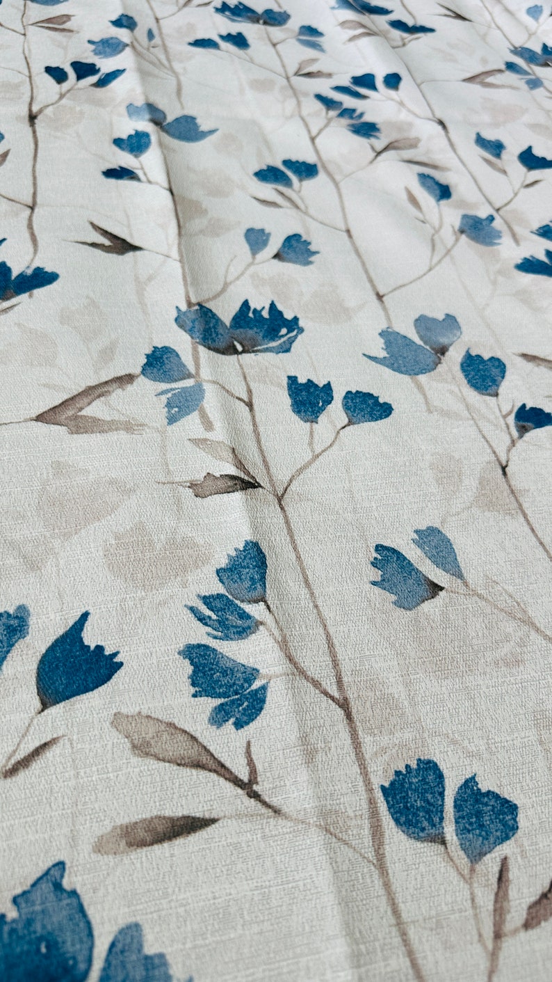 Pu&ograve; includere: Tessuto bianco con un motivo ripetitivo di fiori stilizzati blu e steli marroni.