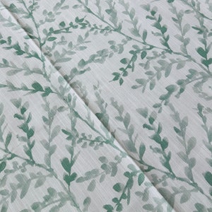 May include: White fabric with a green leafy pattern. The leaves are a watercolor style and are scattered across the fabric.