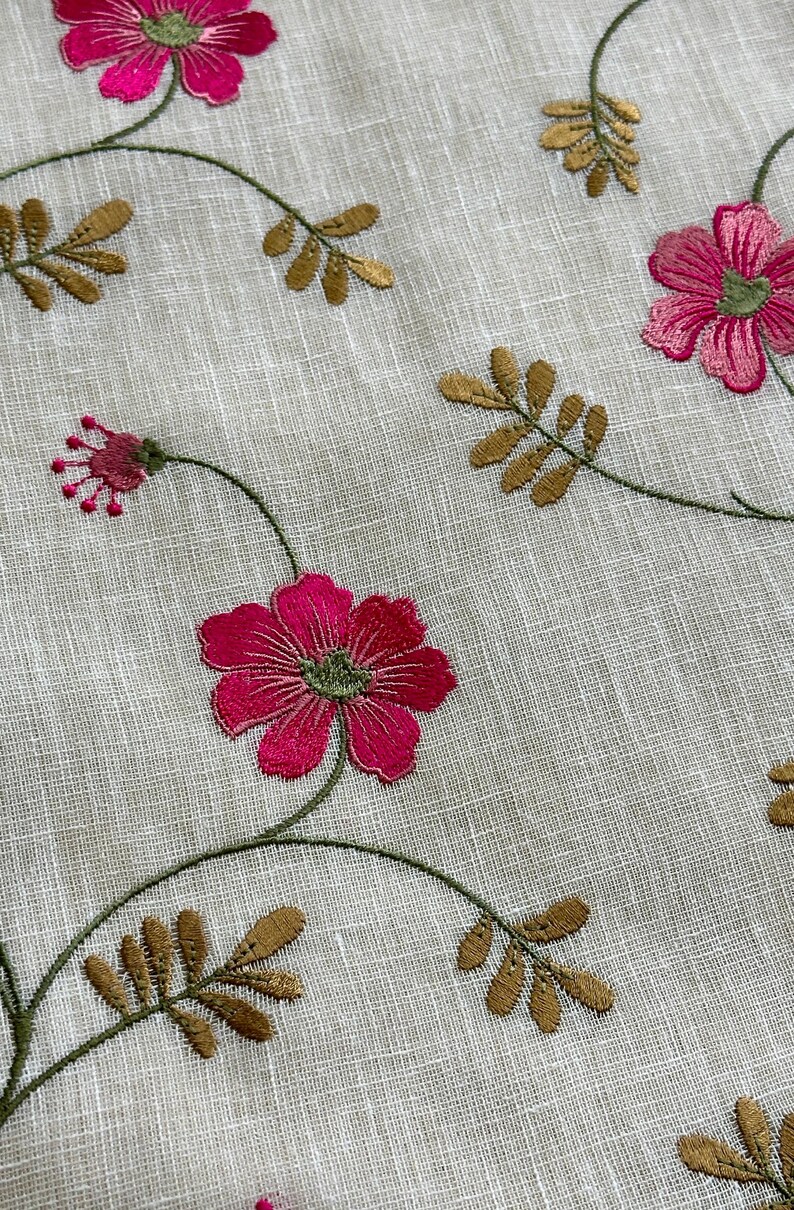 May include: White fabric with embroidered pink flowers and gold leaves. The flowers have a green center.