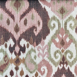 May include: Close-up of a fabric with a repeating pattern in shades of brown, pink, green, and white. The design features stylized, organic shapes reminiscent of ikat textiles, creating a textured, decorative surface.