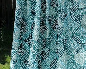 May include: A white fabric curtain with a teal and green geometric pattern. The pattern is made up of repeating circles and diamonds.