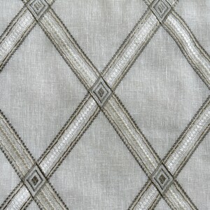 May include: A white fabric with a diamond pattern woven in a brown and white thread.