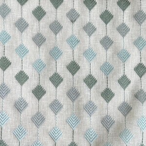 May include: A close-up of a fabric with a repeating pattern of light blue and green diamond shapes. The fabric has a subtle texture and a light gray background.