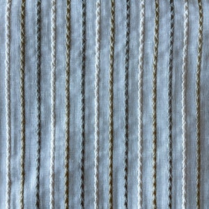May include: White fabric with vertical stripes of beige, gray, and white thread. The stripes are woven into the fabric and create a subtle texture.