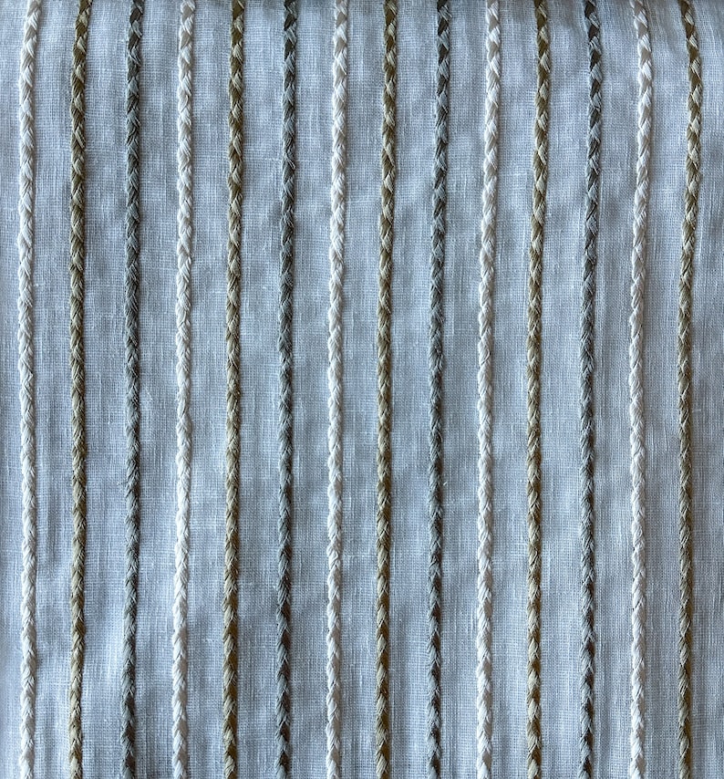 May include: White fabric with vertical stripes of beige, gray, and white thread. The stripes are woven into the fabric and create a subtle texture.
