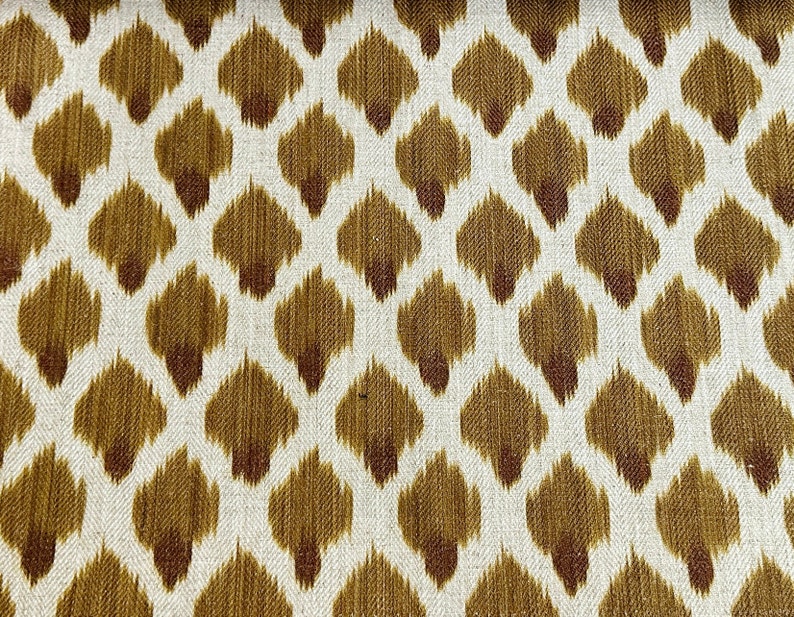May include: A white fabric with a brown and rust colored ikat pattern.