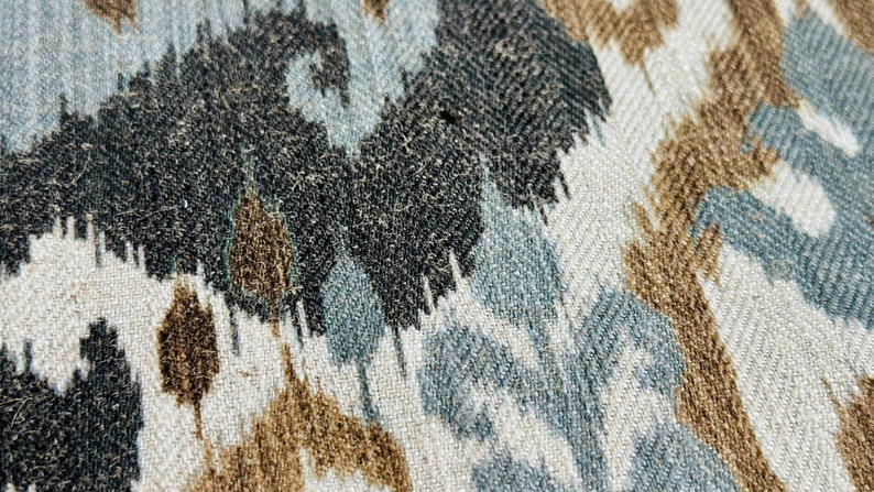 Puede incluir: Primer plano de una tela con un patr&oacute;n tejido en tonos marrones, azules y blancos. El patr&oacute;n se asemeja a hojas o flores abstractas.