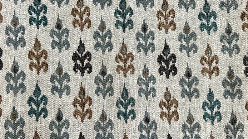 May include: A white fabric with a repeating pattern of stylized leaves in shades of teal, brown, gray, and black.