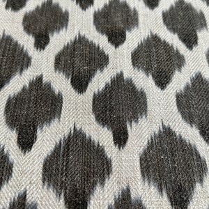 May include: A close-up of a fabric with a white background and a black, abstract, ikat-style pattern.