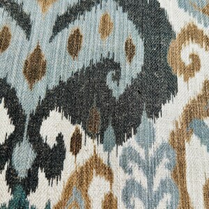 Puede incluir: Primer plano de una tela con un patr&oacute;n ikat azul, marr&oacute;n y blanco. La tela tiene una textura tejida y un brillo sutil.