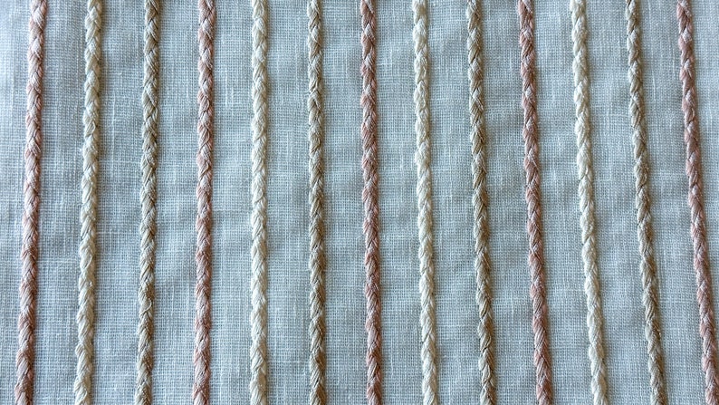 Puede incluir: Primer plano de una tela tejida con rayas verticales en beige y rosa claro.