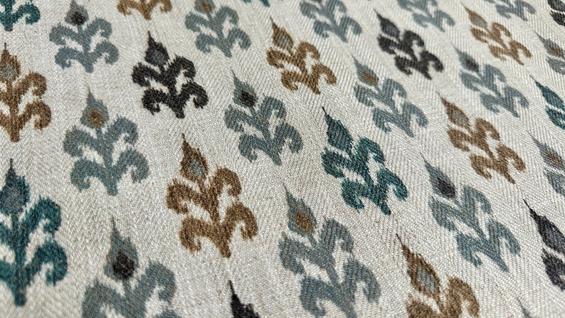 May include: A white fabric with a repeating pattern of blue, brown, and black stylized floral designs.