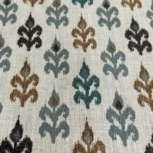 May include: A white fabric with a repeating pattern of brown, teal, and black stylized floral motifs.