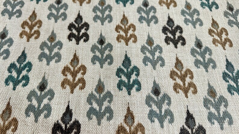 May include: A white fabric with a repeating pattern of brown, teal, and black stylized floral motifs.