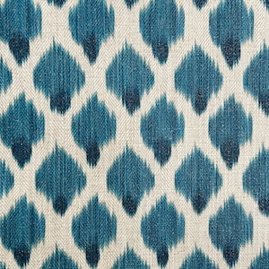 May include: A close-up of a fabric with a repeating pattern of blue and white ikat-style shapes. The fabric has a textured, woven look.
