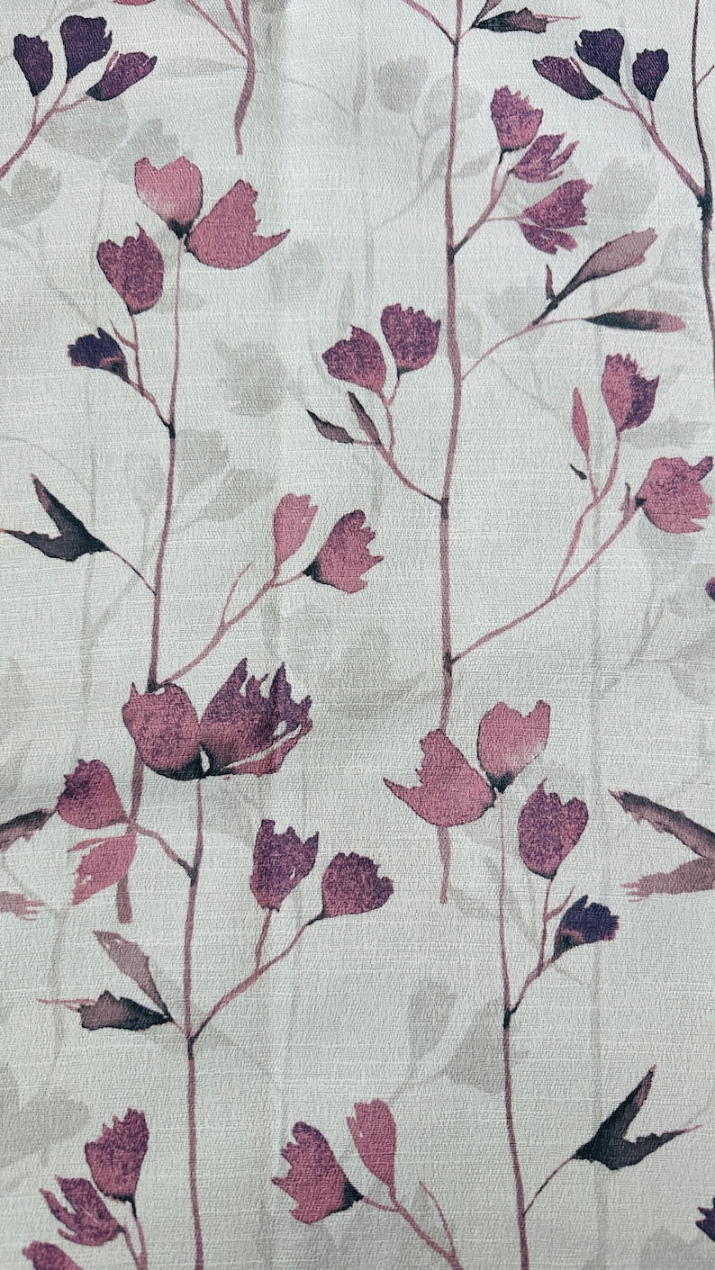 May include: A white fabric with a repeating pattern of purple watercolor flowers and stems. The flowers are stylized and resemble a simple blossom.