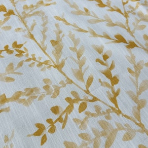 May include: White fabric with a subtle pattern of gold-colored leaves and branches.