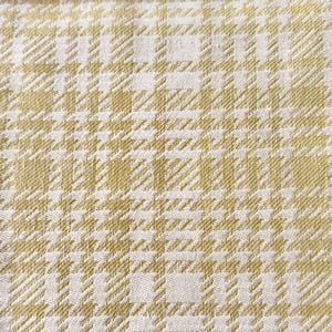 May include: A woven fabric featuring a repeating houndstooth pattern in shades of light olive green and off-white. The textile displays a dense, textured weave with a consistent grid-like structure throughout the entire surface area.