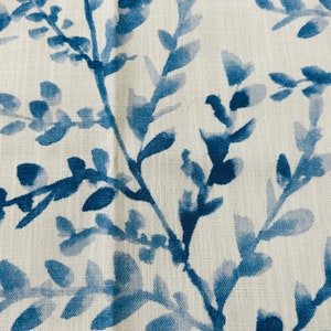 May include: Close-up of a fabric with a repeating pattern of blue watercolor-style leaves and branches against a white background. The design has a natural, botanical theme, suitable for home decor or apparel.