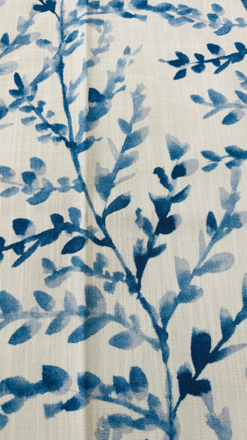 May include: Close-up of a fabric with a repeating pattern of blue watercolor-style leaves and branches against a white background. The design has a natural, botanical theme, suitable for home decor or apparel.