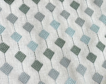 May include: A white fabric with a repeating pattern of blue and green diamond shapes. The diamonds are made of a textured, embroidered design.