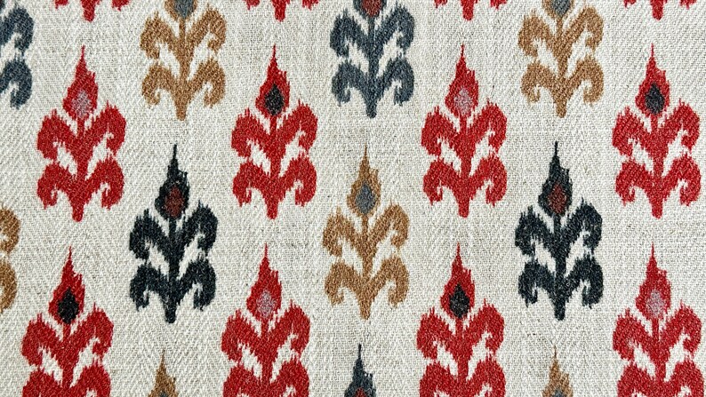 May include: A white fabric with a repeating pattern of red, black, and brown stylized floral designs.
