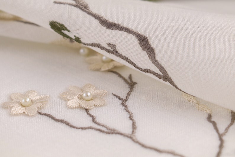 May include: White fabric with embroidered brown branches and beige flowers with pearl centers.